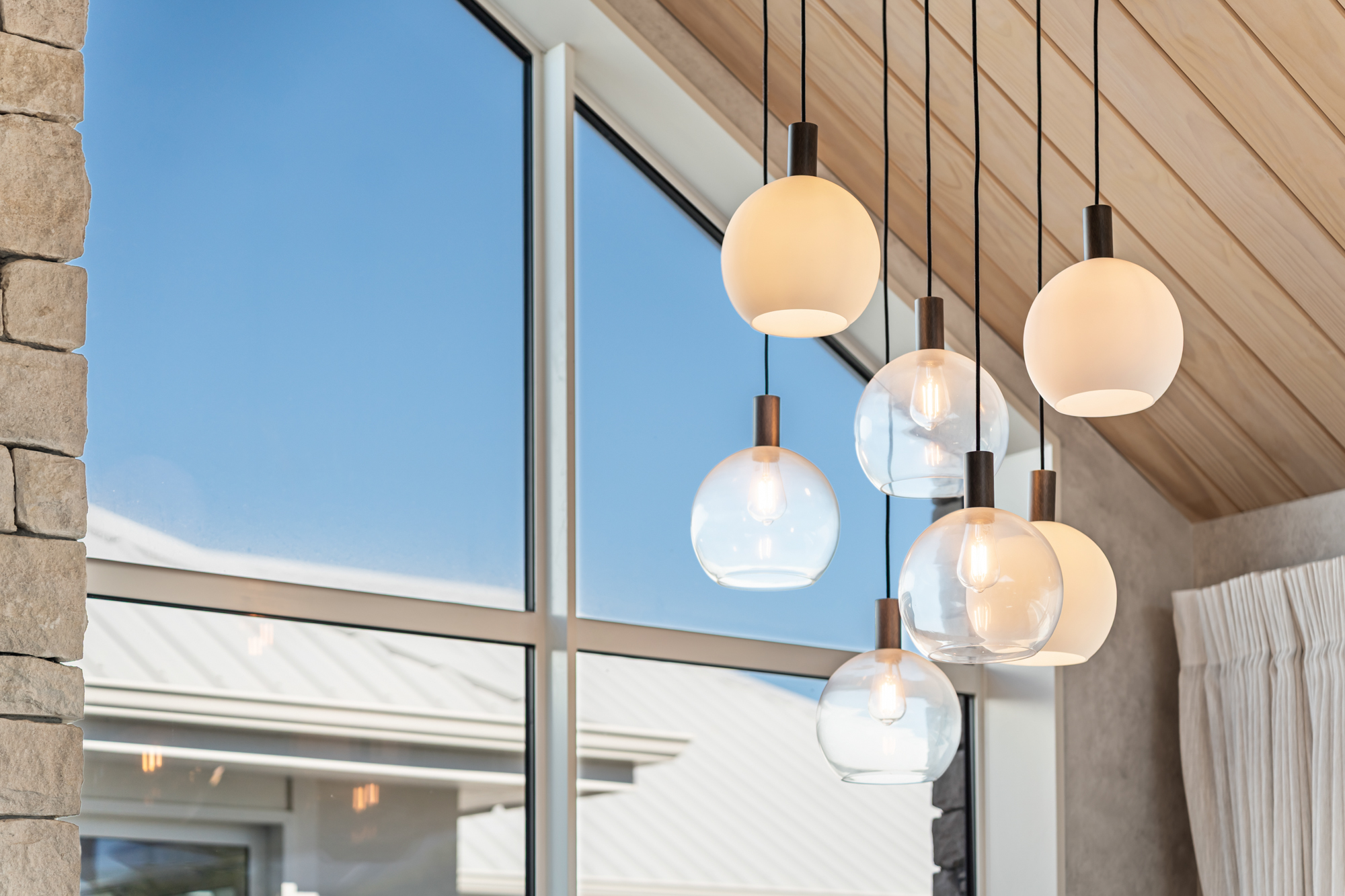 Marine Parade - architectural pendant light cluster against cedar ceiling and stone wall